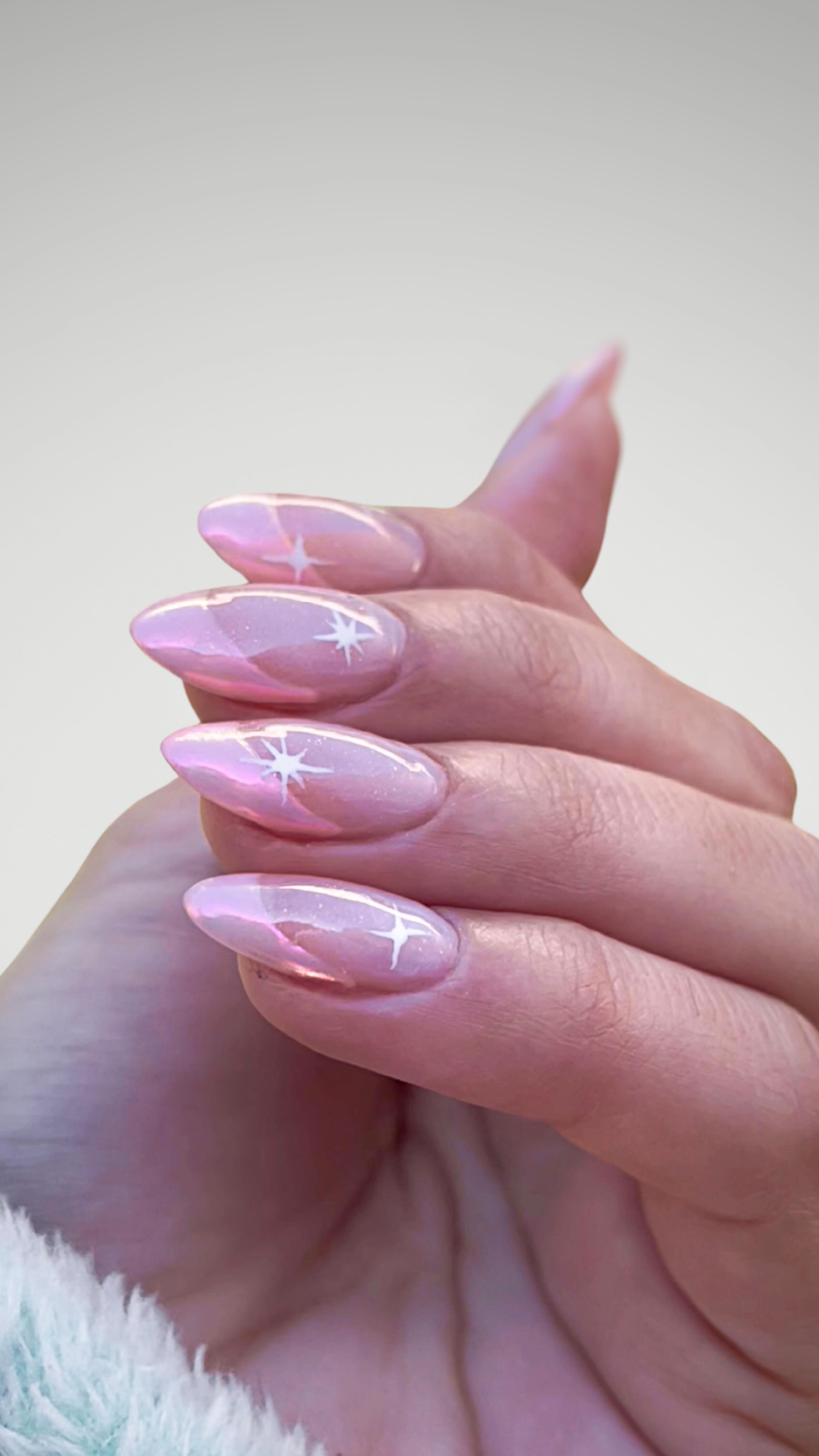 Uñas almendradas rosa cromado con estrellas pintadas a mano en blanco